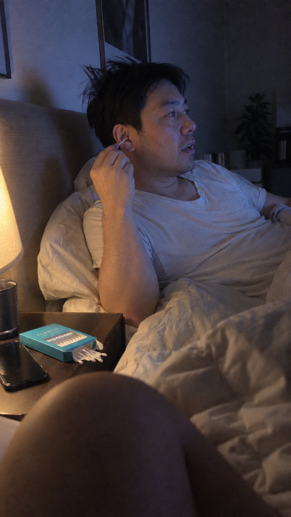Man in bed at night cleaning his outer ear